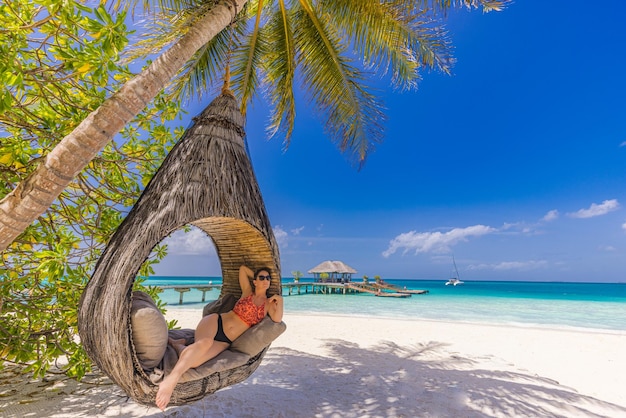 Jeune belle femme maillot de bain cheveux blonds relaxant dans un hamac de luxe tropical mer ciel plage incroyable