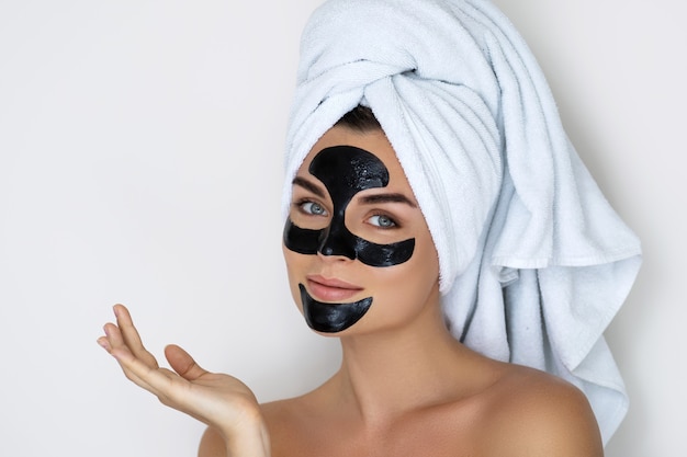 Jeune et belle femme avec un masque peel-off noir sur son visage