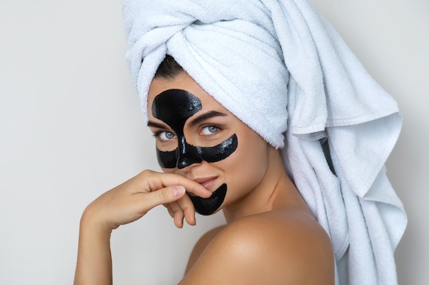 Jeune et belle femme avec un masque peel-off noir sur son visage