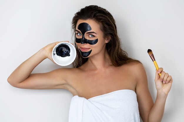 Jeune et belle femme avec un masque peel-off noir sur son visage