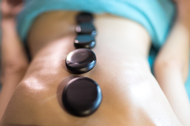 Photo jeune belle femme et massage aux pierres dans un spa de beauté.