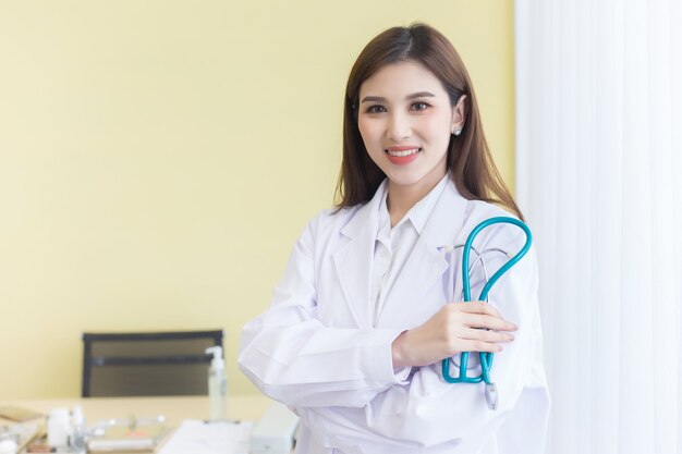 Jeune belle femme médecin asiatique debout avec les bras croisés heureux et souriant à l'hôpital