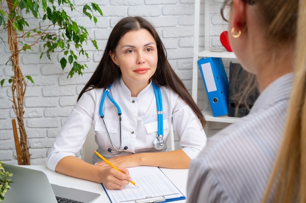 Jeune belle femme médecin ayant une conversation avec son patient à l'hôpital