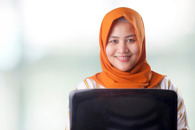 jeune et belle femme musulmane asiatique souriante tenant un ordinateur portable étudiante ou femme d'affaires réussie