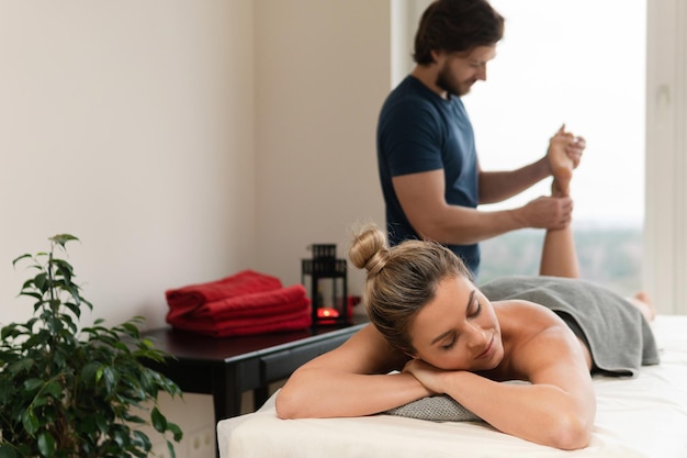 Jeune et belle femme pendant le massage des pieds dans une clinique de massage professionnelle