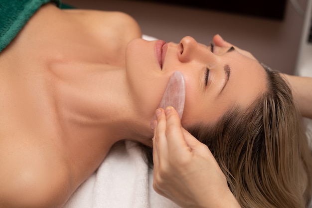 Jeune et belle femme pendant le massage traditionnel chinois - Gua Sha. Photo en gros plan.