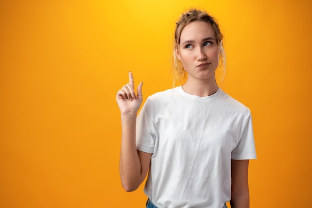 Jeune belle femme pensant regardant sur le côté sur fond jaune