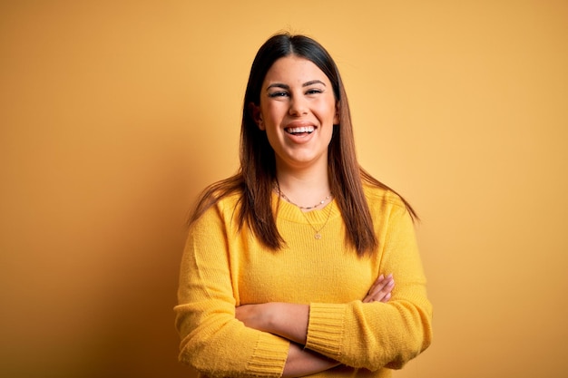 Jeune belle femme portant un chandail décontracté sur fond isolé jaune visage heureux souriant avec les bras croisés regardant la caméra Personne positive