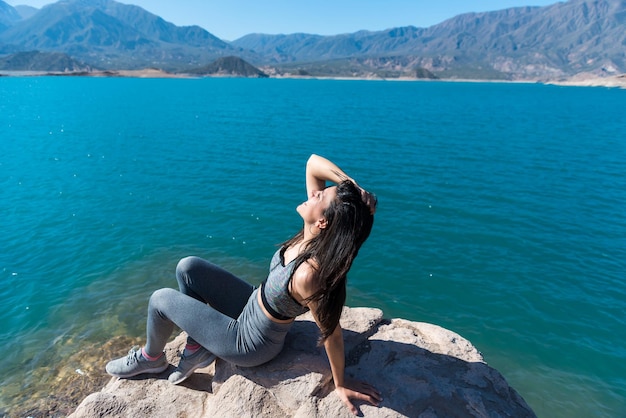 Jeune et belle femme prenant un bain de soleil sur un lac entre les montagnes sportive