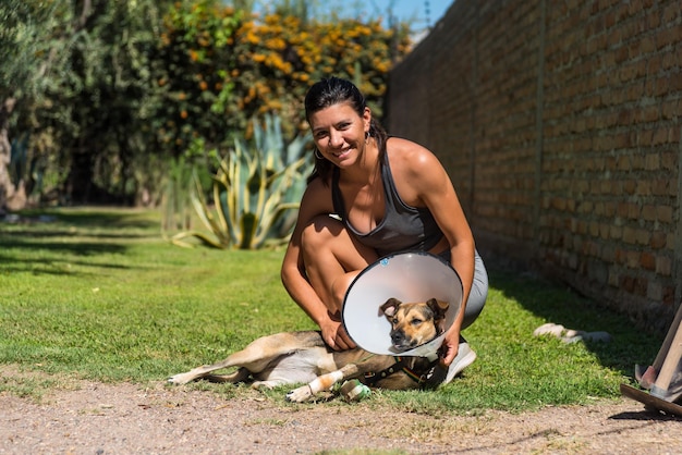 Jeune et belle femme prenant soin de son chien blessé sur l'herbe par une journée ensoleillée