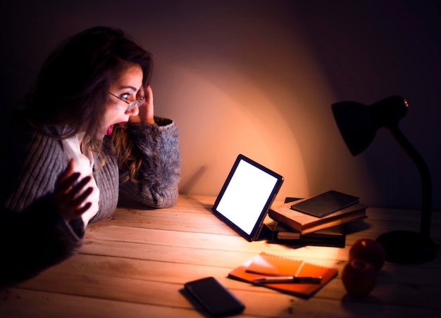 Une jeune et belle femme qui travaille sur une tablette la nuit.