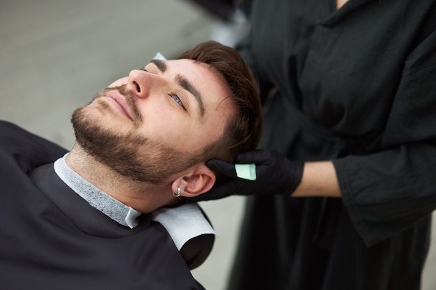 Jeune belle femme de race blanche coiffeur coupe barbe bel homme au salon de coiffure moderne