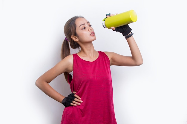 Jeune belle femme sportive asiatique buvant de l'eau après l'entraînement sur fond blanc