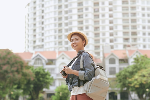 Jeune belle femme de voyageur sac à dos asiatique à l'aide d'un appareil photo numérique compact et sourire