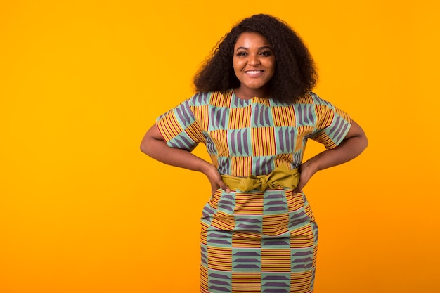 Jeune belle fille afro-américaine avec une coiffure afro. Portrait sur fond jaune. Fille