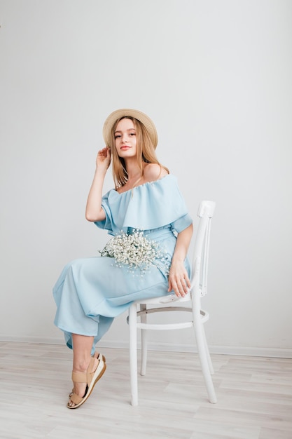 Photo jeune belle fille aux cheveux longs et chapeau posant avec un bouquet de fleurs blanches. tonifiant.