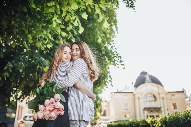 jeune belle fille blonde embrasse sa mère d'âge moyen dans les rues de la ville.