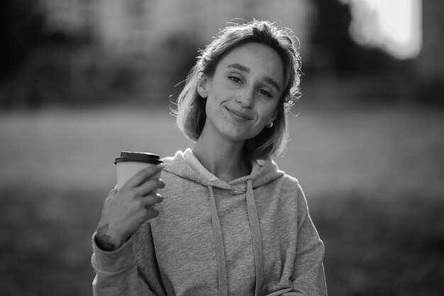 Jeune belle fille boit du lat dans un gobelet en papier dans la rue photo noir et blanc