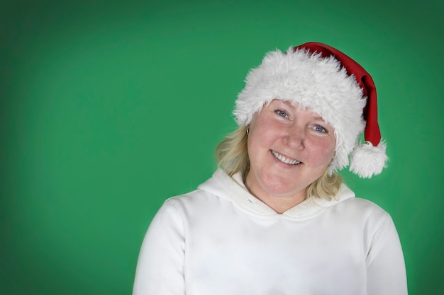 Photo jeune belle fille en bonnet de noel de noël sur fond vert isolé avec un visage heureux debout et souriant avec un sourire confiant.