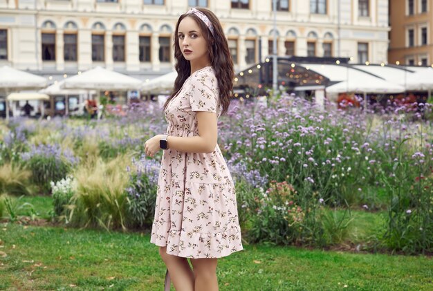 Jeune belle fille brillante dans une robe d'été en riant dans le parc de la ville