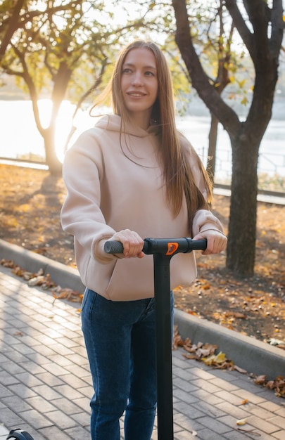 Jeune belle fille à cheval dans le parc sur des scooters électriques par une chaude journée d'automne.