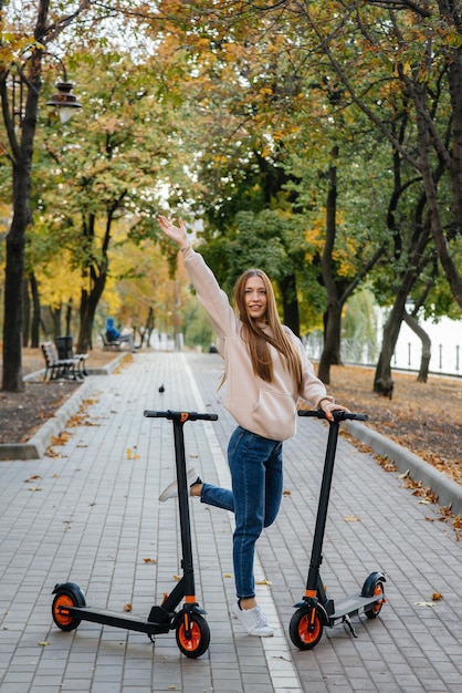 Jeune belle fille à cheval dans le parc sur des scooters électriques par une chaude journée d'automne.