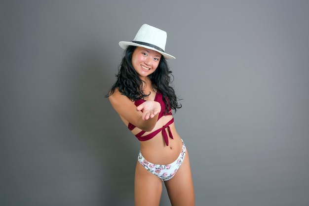 Jeune et belle fille chinoise en bikini tendant la main avec un grand sourire