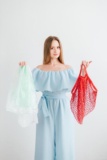 Photo jeune belle fille compare un sac à cordes utile et des sacs en plastique nocifs. le concept de zéro déchet. tonifiant.