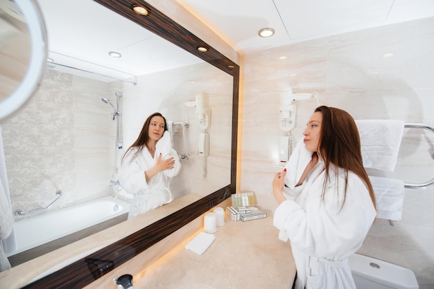 Jeune belle fille dans une belle salle de bain blanche. Bon matin frais à l'hôtel.