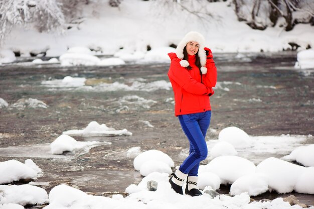 Jeune belle fille dans la forêt d'hiver près de la rivière.