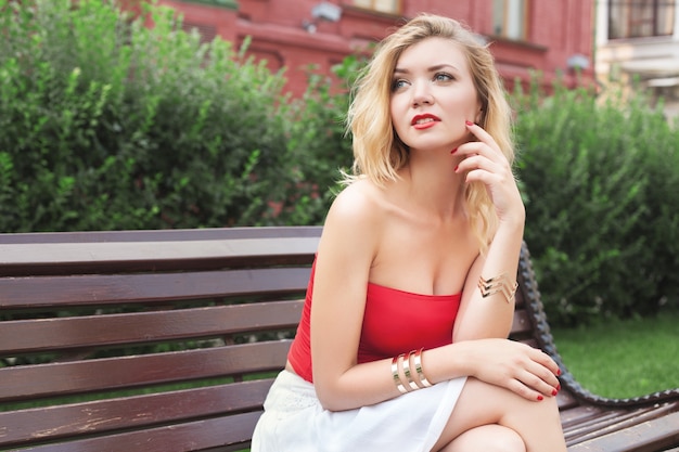 Jeune belle fille dans une jupe blanche et un haut rouge. marcher dans le parc et la ville