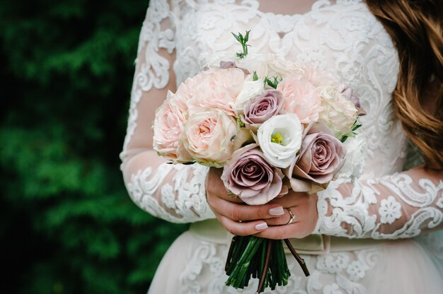 Jeune belle fille dans une robe élégante est debout et tenant un bouquet de fleurs