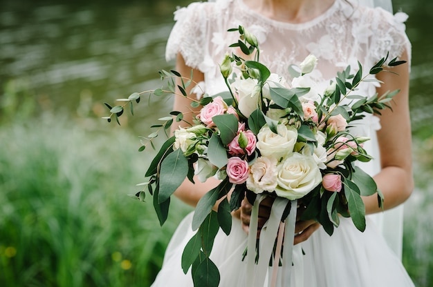 Jeune belle fille dans une robe élégante est debout et tenant le bouquet de la main