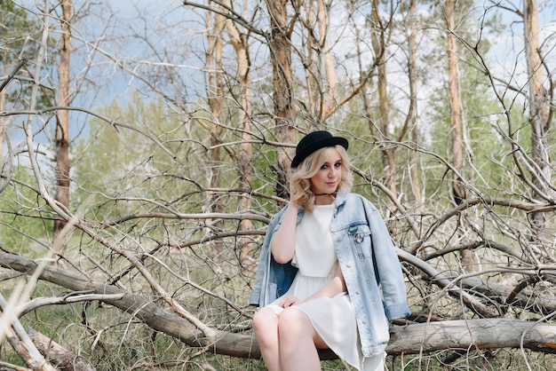 Jeune belle fille dans une veste en jean dans la forêt en été avec des arbres secs 1