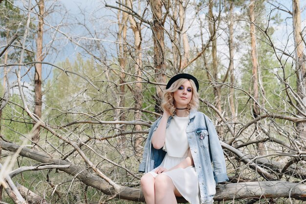 Jeune belle fille dans une veste en jean dans la forêt en été avec des arbres secs 1