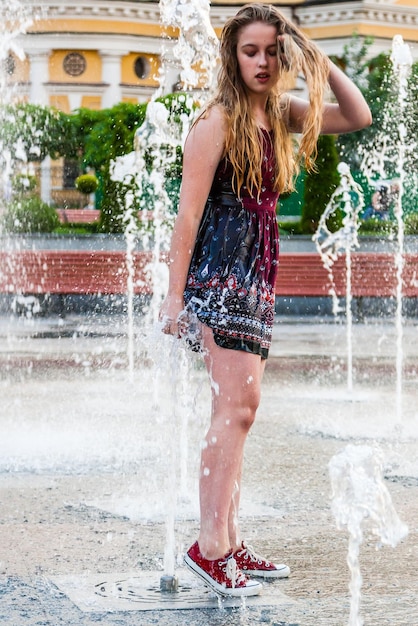 La jeune belle fille danse dans une fontaine