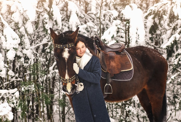 Jeune belle fille embrasse un cheval dans le parc en hiver