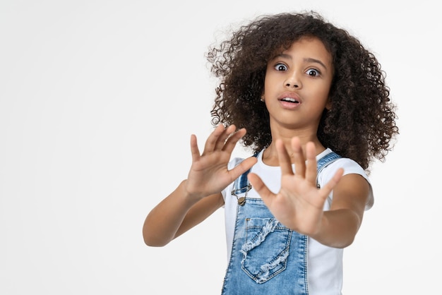 Jeune belle fille enfant avec expression de peur geste d'arrêt avec les mains debout