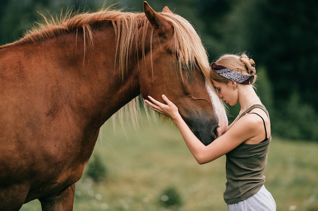 Jeune belle fille étreignant le cheval à la nature.