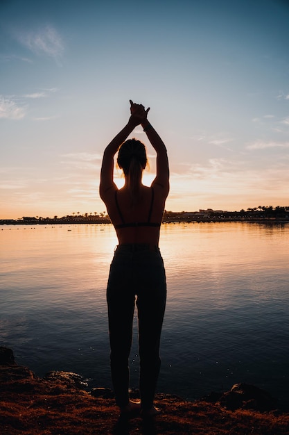 Jeune belle fille faisant l'échauffement à l'aube du bord de mer