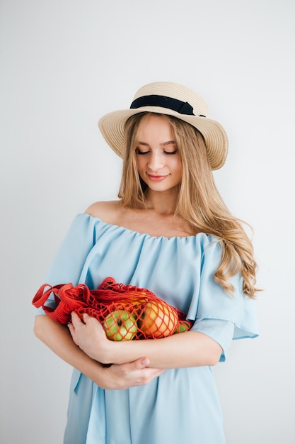 Jeune belle fille avec des fruits frais dans un sac à cordes. Le concept de zéro déchet. Tonifiant.