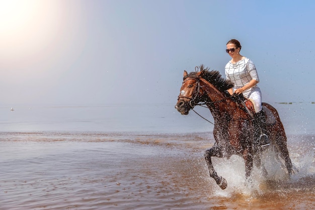 La jeune belle fille galope très vite sur l'eau un jour ensoleillé chaud