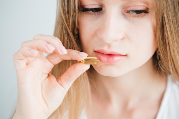 Photo jeune belle fille malade met une pilule dans sa bouche. comprimés gélules multicolores, vitamines, compléments alimentaires. visage en gros plan. tonifiant.