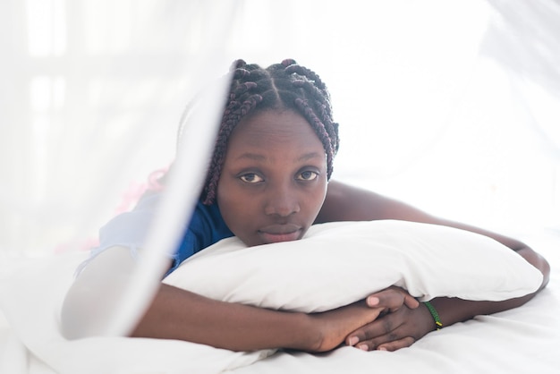 Jeune belle fille noire se réveillant dans le lit de la chambre