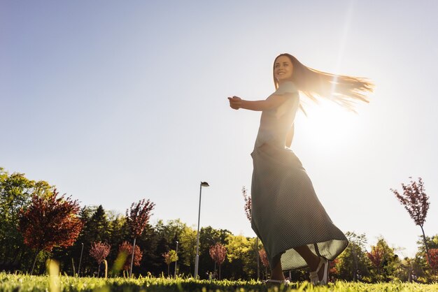 Jeune belle fille avec plaisir danse dans le parc, riant