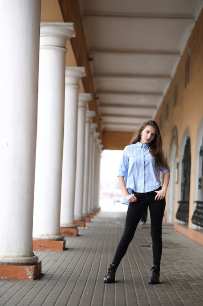 Jeune belle fille sur une promenade près d'un bâtiment avec une colonne