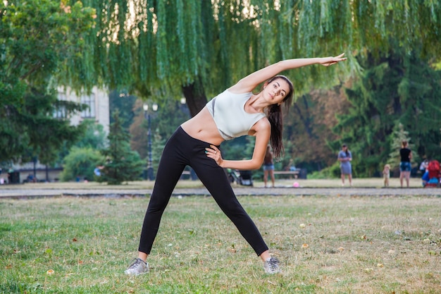 Jeune belle fille sexy heureuse s'étend dans le fond de gens de jardin de parc avec les cheveux noirs