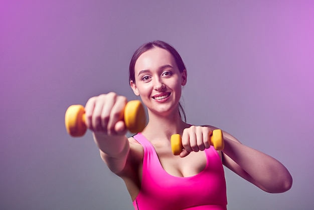 Jeune belle fille sportive en leggings et un haut fait des exercices avec des haltères. Mode de vie sain.