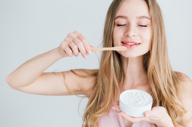 Jeune belle fille tenant une brosse à dents en bambou utile et un pot de poudre de dent. Le concept d'un mode de vie sain, respectueux de l'environnement et zéro déchet. Tonifiant.