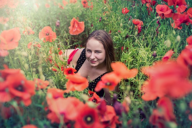 Jeune belle fille en tenue de sport allongée dans le champ de coquelicots profitez de la liberté en été